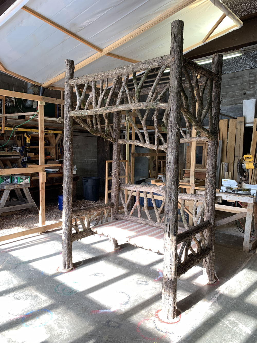 Outdoor sitting shelter built in the rustic style using logs and branches titled the Fishman Sitting Shelter