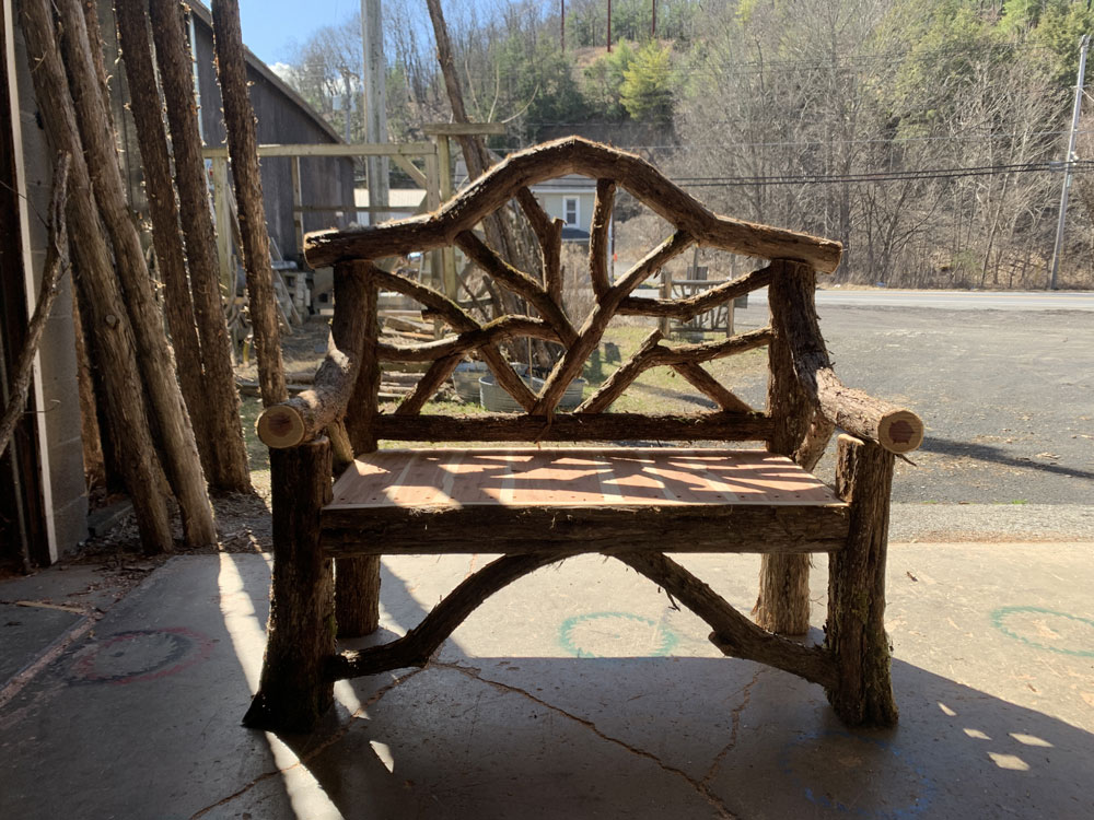 Outdoor rustic garden bench built using bark-on trees and branches titled the Garrison Bench