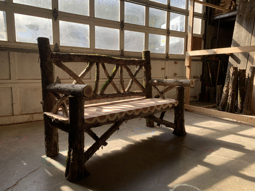 Outdoor rustic garden bench built using bark-on trees and branches titled the Milan Bench