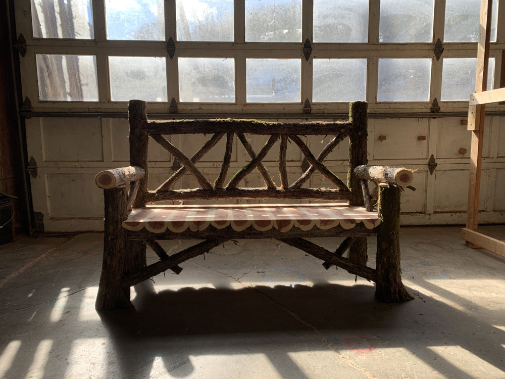Outdoor park bench built in the rustic style using logs and branches titled the Milan Bench