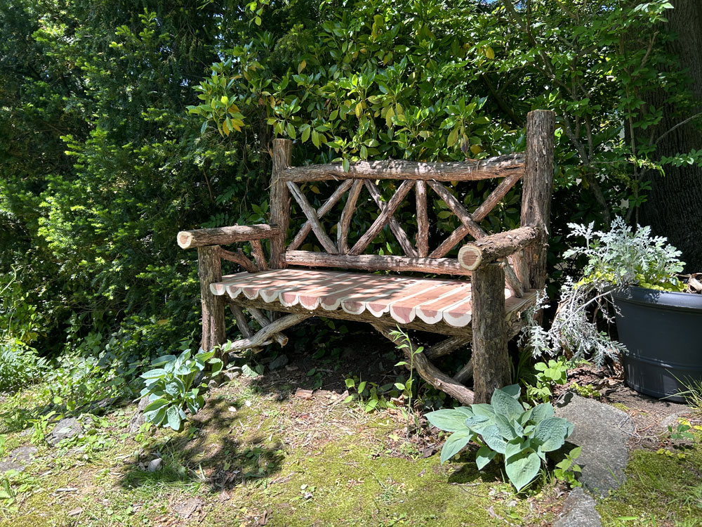 Outdoor park bench built in the rustic style using logs and branches titled the Milan Bench