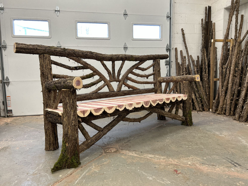 Rustic bench custom built using cedar trees and branches titled the Catskill Bench 