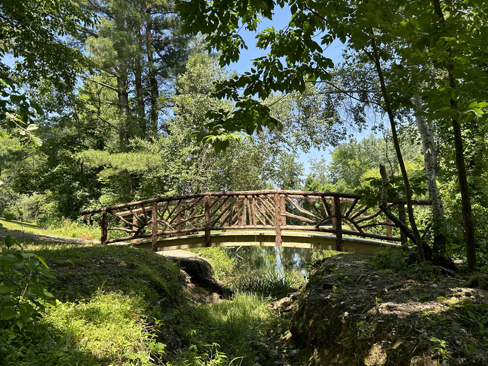 Bridge built in the rustic style using logs and branches titled the Hillsdale Bridge 