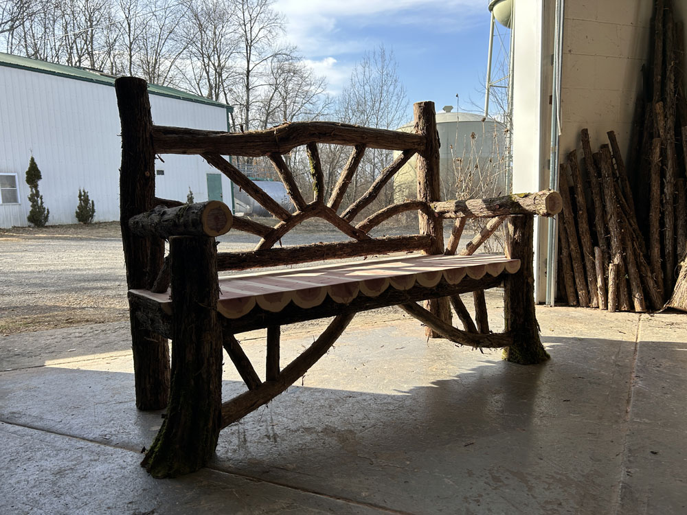 Outdoor park bench built in the rustic style using logs and branches titled the Millbrook Sunburst Bench