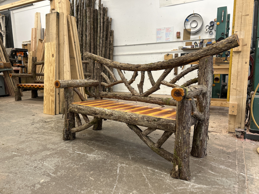 Exterior twig bench built from cedar logs with a coat of oil titled the Fallings Waters Bench