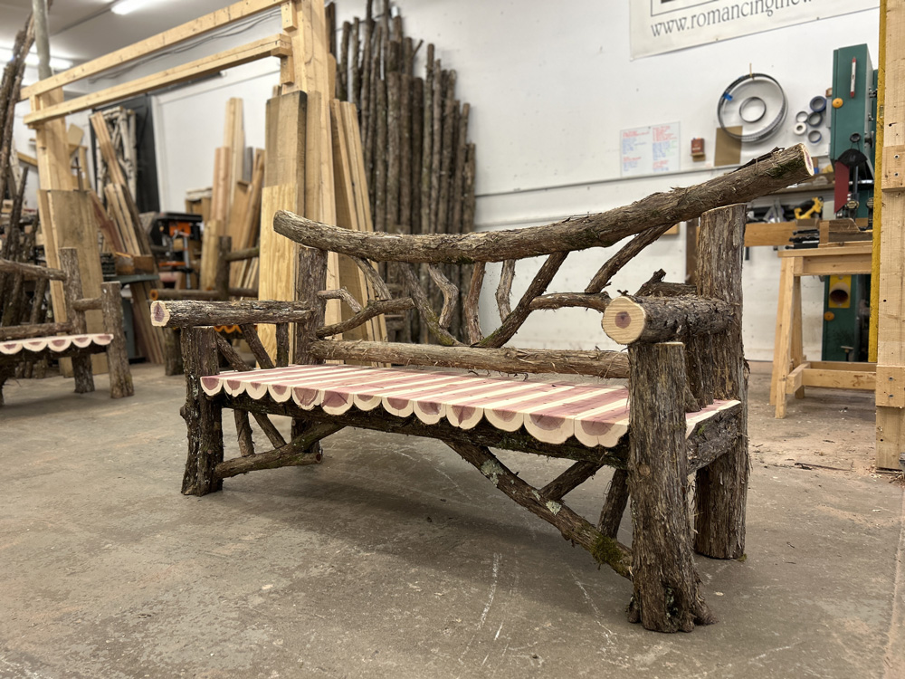 Outdoor park bench built in the rustic style using logs and branches titled the Falling Waters Bench