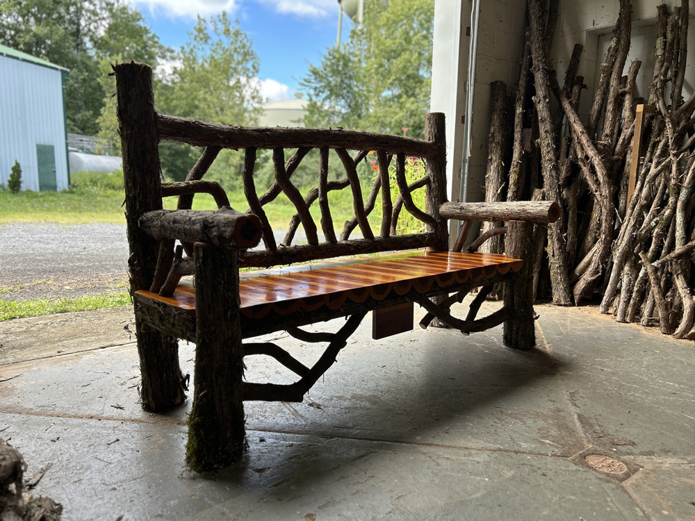 Outdoor rustic garden bench built using bark-on trees and branches titled the Mohonk Bench