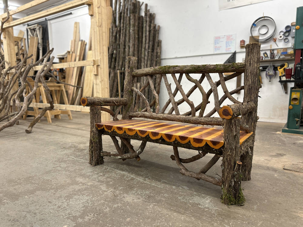 Outdoor rustic garden bench built using bark-on trees and branches titled the Putnam Bench
