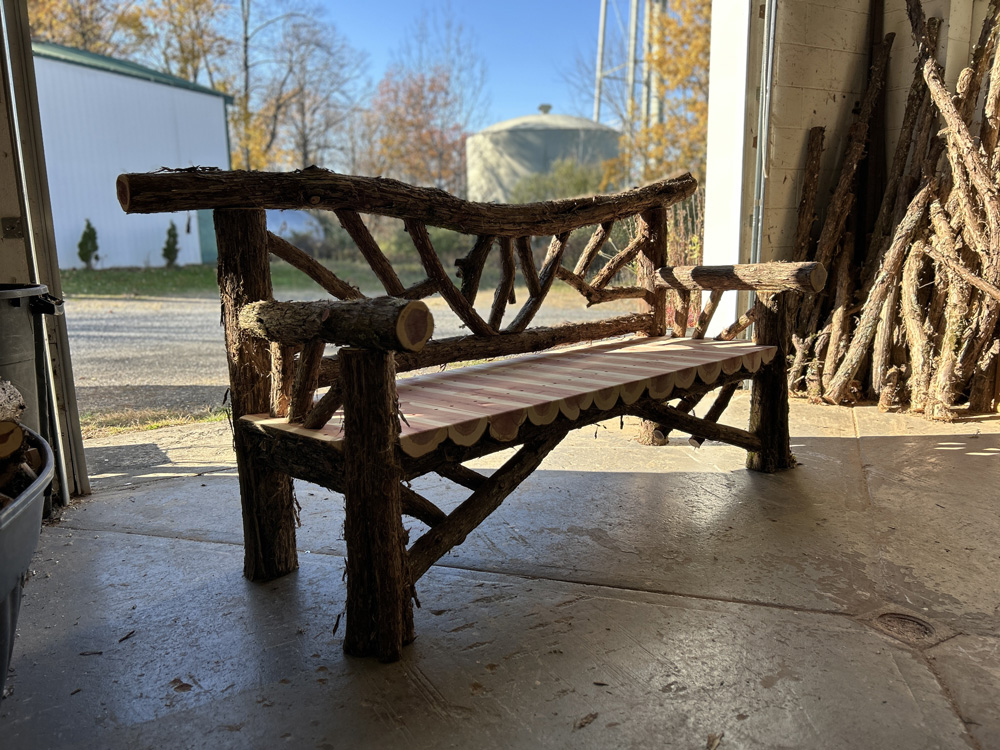 Outdoor rustic garden bench built using bark-on trees and branches titled the Falling Waters Bench