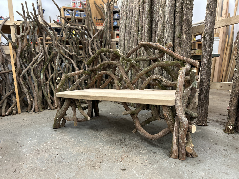 Outdoor rustic park bench built using mountain laurel trees and branches titled the Olana Bench