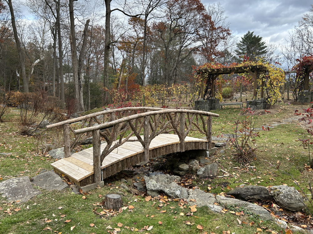 Outdoor park bench built in the rustic style using logs and branches titled the Millbrook Sunburst Bench