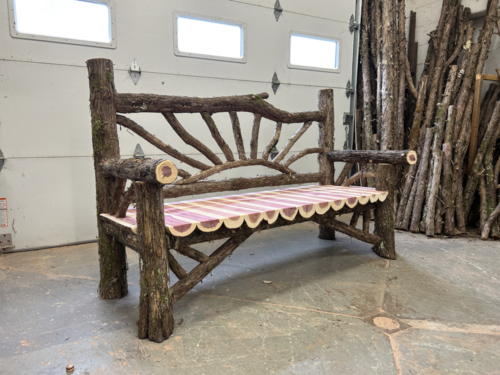 Outdoor rustic garden bench built using bark-on trees and branches titled the Falling Waters Bench