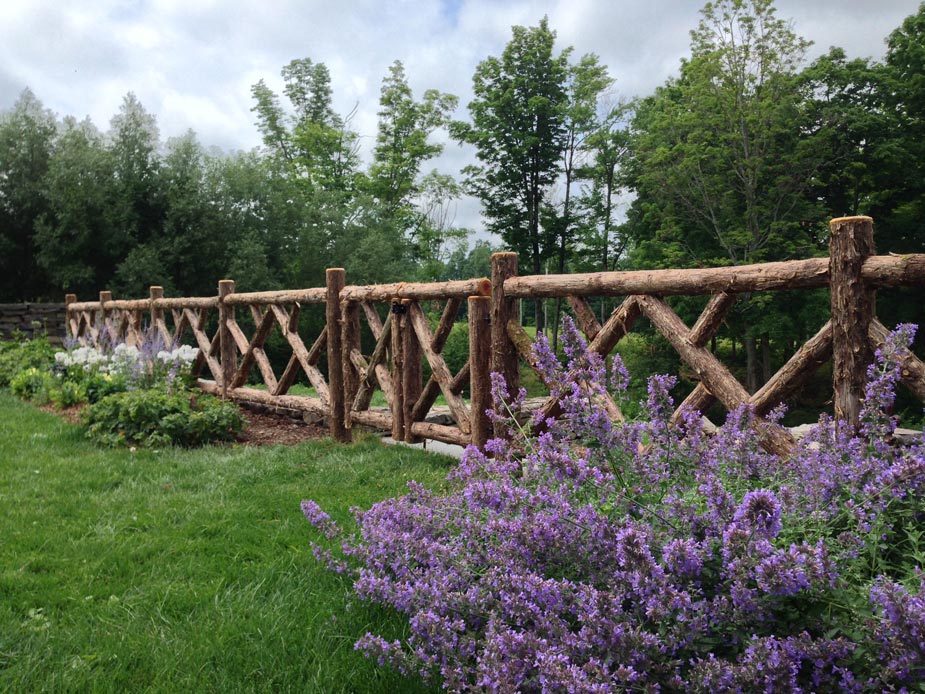 Rustic garden fencing built using bark-on trees and branches titled the Old Chatham Fencing
