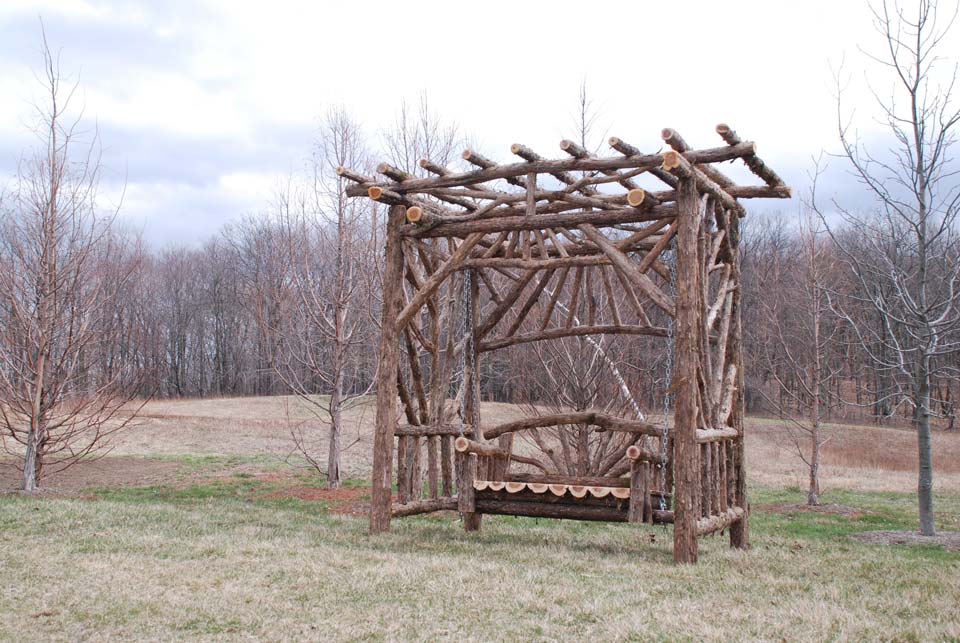 Exterior twig bench swing built from cedar logs titled the Midler Bench Swing