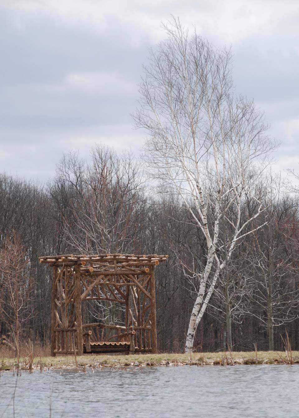 Outdoor rustic garden bench swing built using bark-on trees and branches titled the Midler Bench Swing
