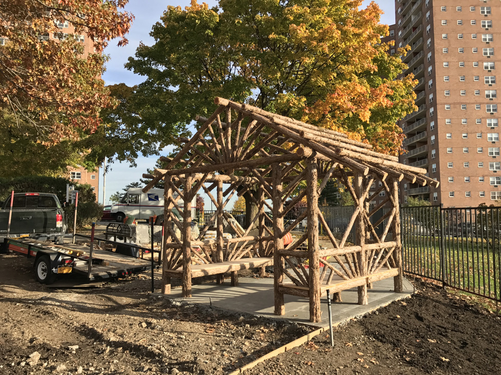 Outdoor sitting shelter built in the rustic style using logs and branches titled the Skyview Entrance Arbor
