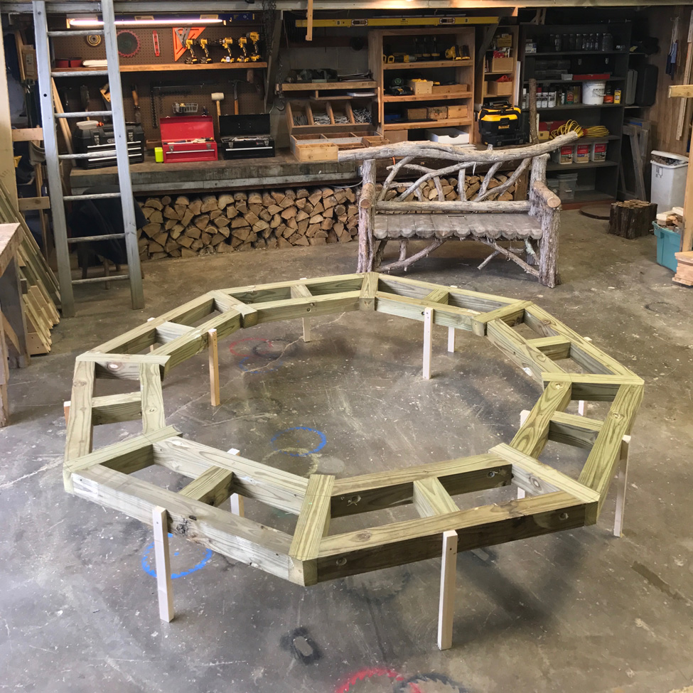 Outdoor rustic bench built around a tree constructed using bark-on trees and branches titled the Skyview Tree Bench