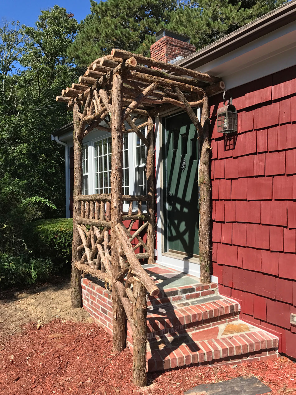 Rustic natural arbor made from bark-on cedar logs, twigs, and branches titled the Melikan Entrance Arbor