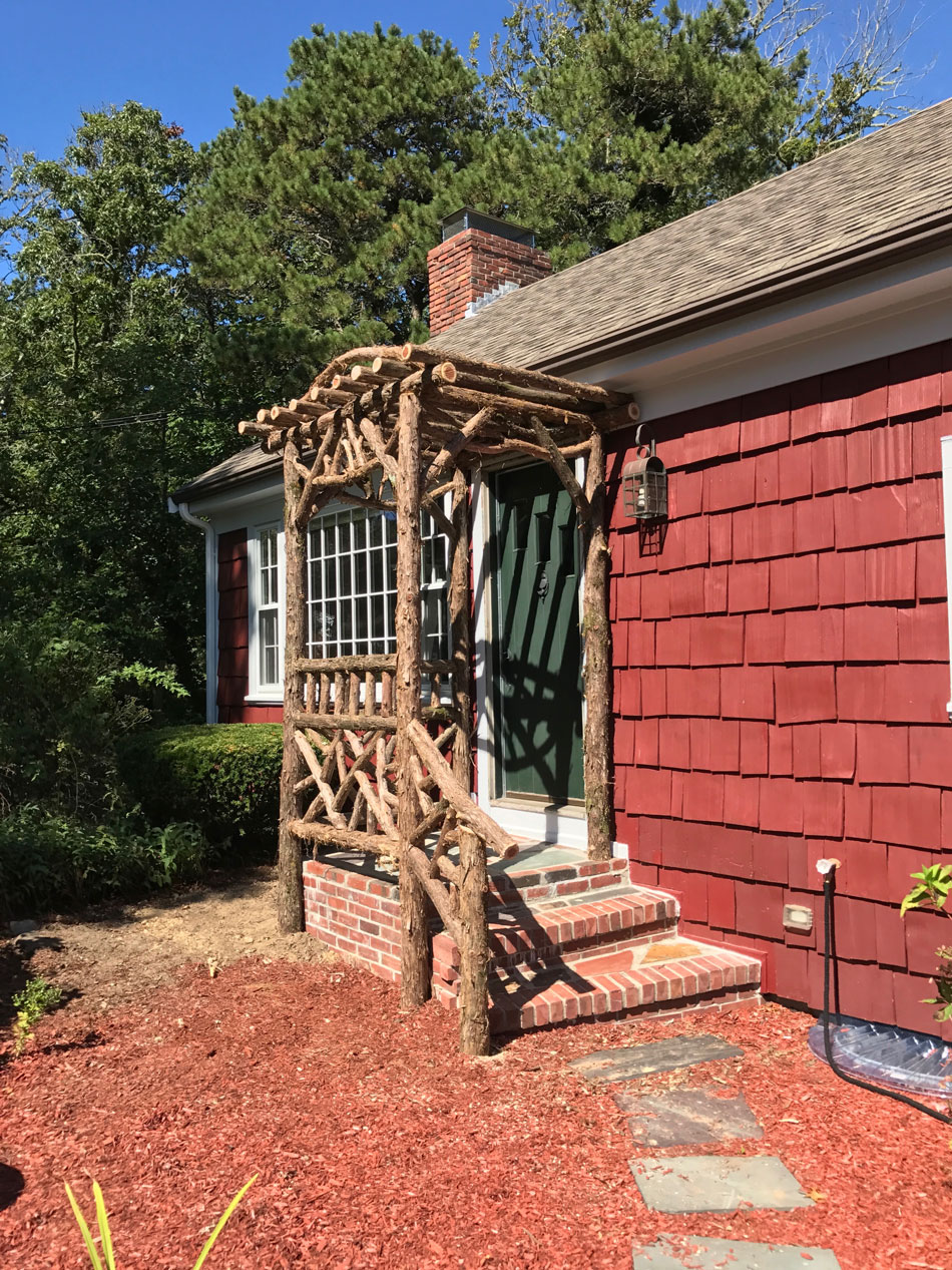 Natural wood rustic arbor built with trees and branches titled the Melikan Entrance Arbor