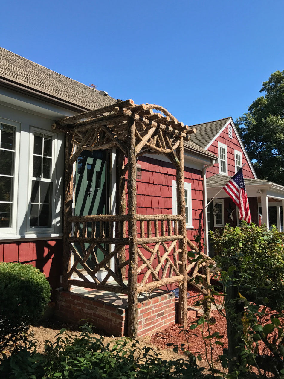 Natural wood rustic arbor built with trees and branches titled the Melikan Entrance Arbor