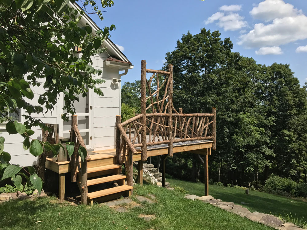 Deck railings built in the rustic style using logs and branches titled the Burroughs Deck Railings