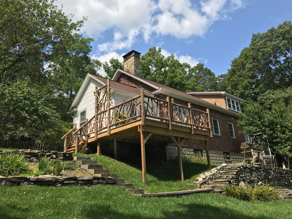 Deck railings built in the rustic style using logs and branches titled the Burroughs Deck Railings