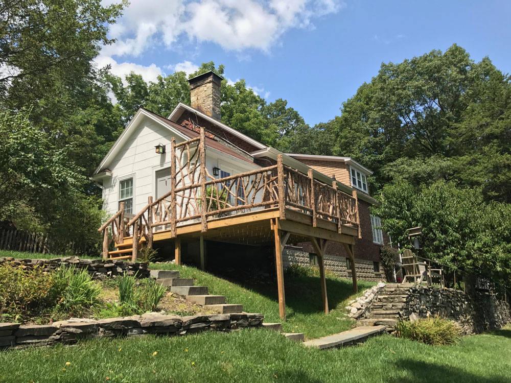 Rustic deck railings built using bark-on trees and branches titled the Burroughs Deck Railings