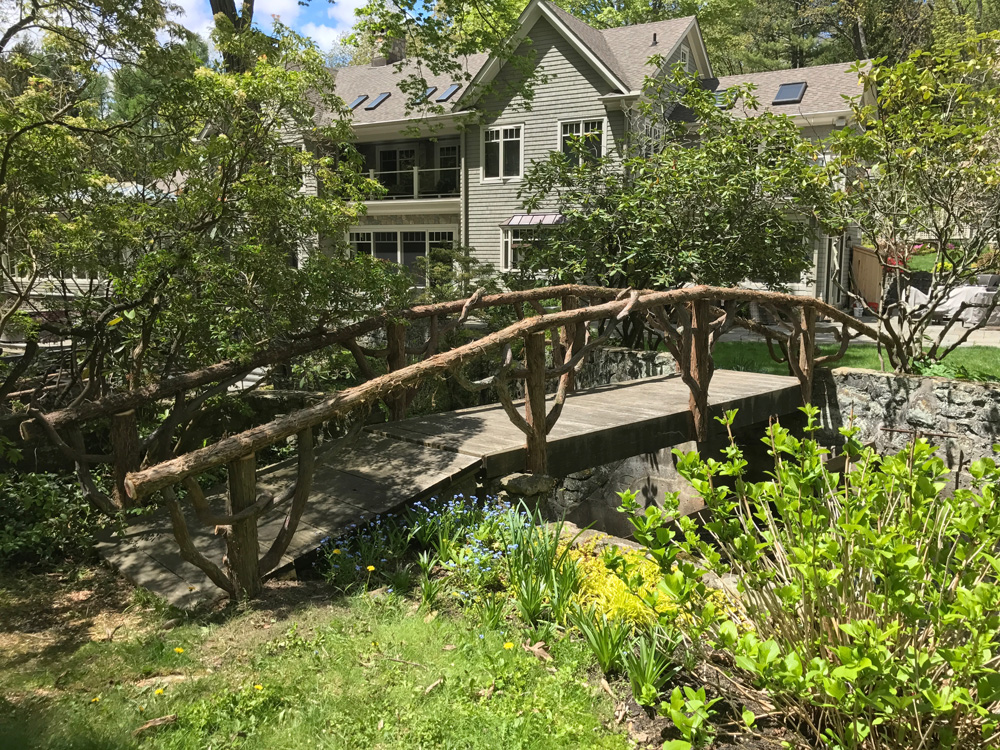 Natural wood bridge built with trees and branches titled the Milltown Bridge's