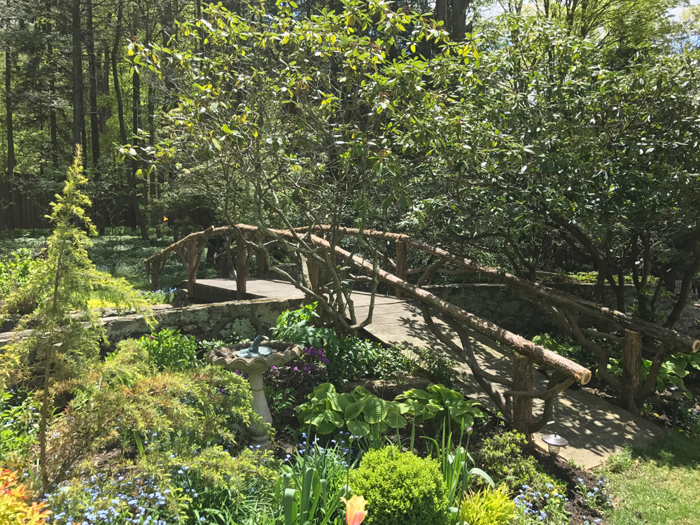 Rustic bridge built using bark-on trees and branches titled the Milltown Bridge's