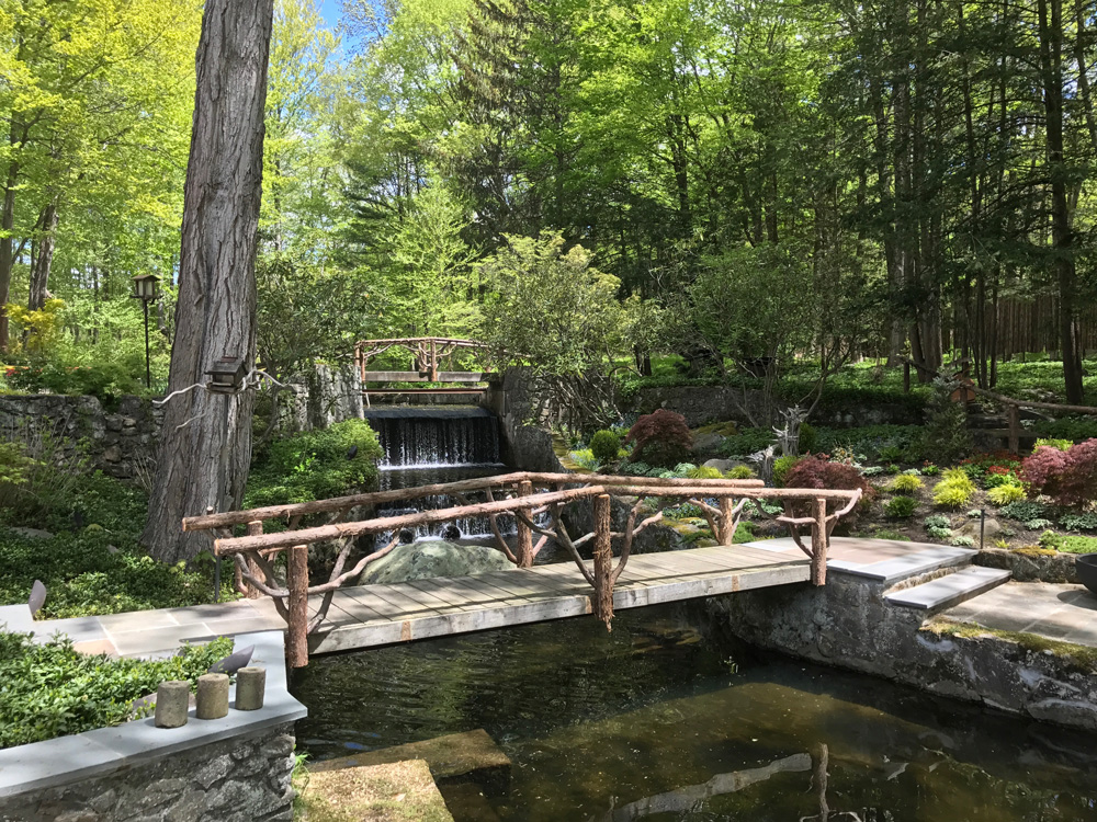 Rustic bridge built using bark-on trees and branches titled the Milltown Bridge's