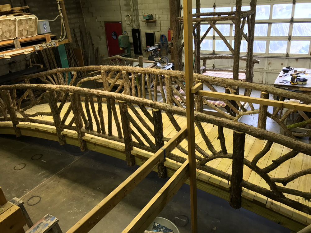 Rustic bridge built using bark-on trees and branches titled the Storm's Crossing