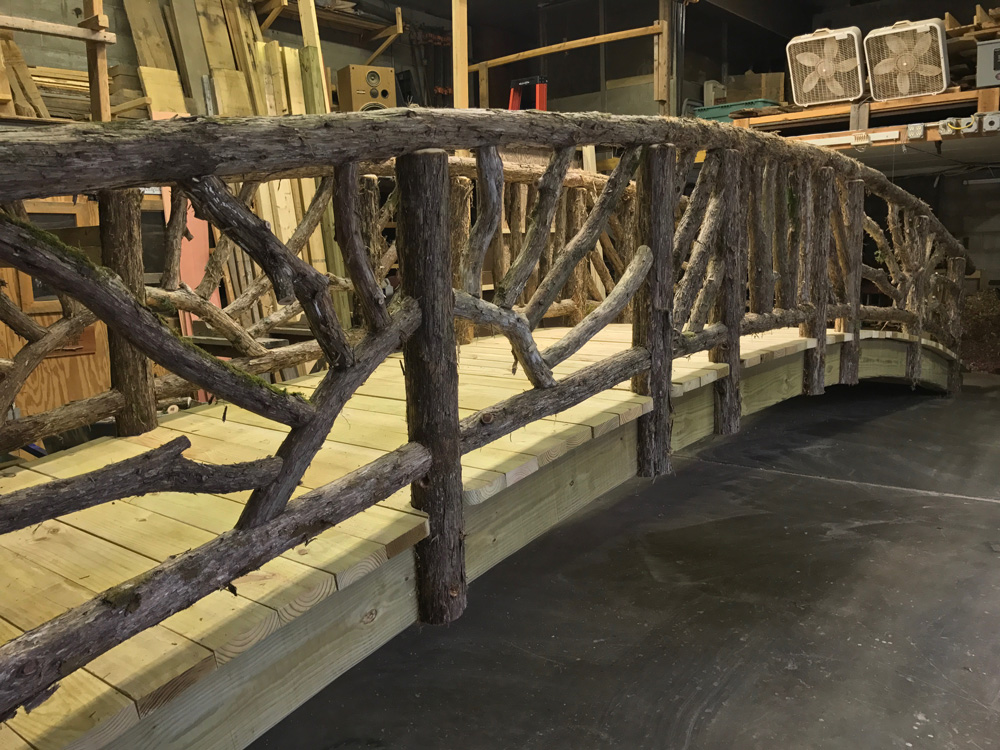 Bridge built in the rustic style using logs and branches titled the Storm's Crossing
