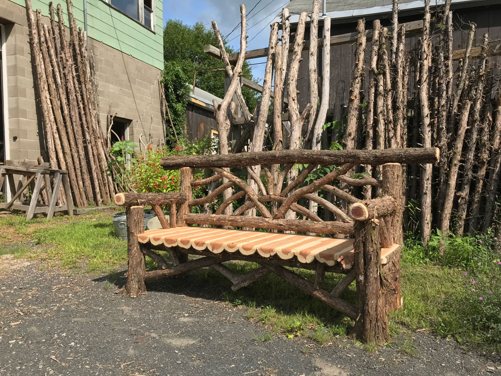 Outdoor park bench built in the rustic style using logs and branches.