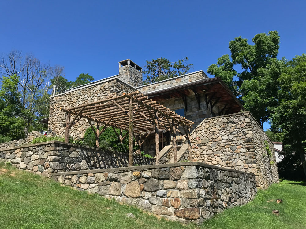 Rustic natural pergola made from bark-on cedar logs, twigs, and branches titled the Wildwood Pergola
