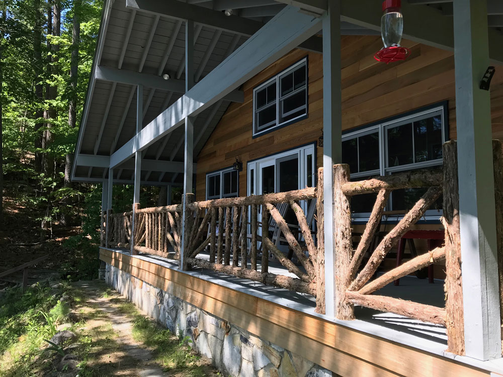 Rustic railings built using bark-on trees and branches titled the Porch Railings at Hullets Landing