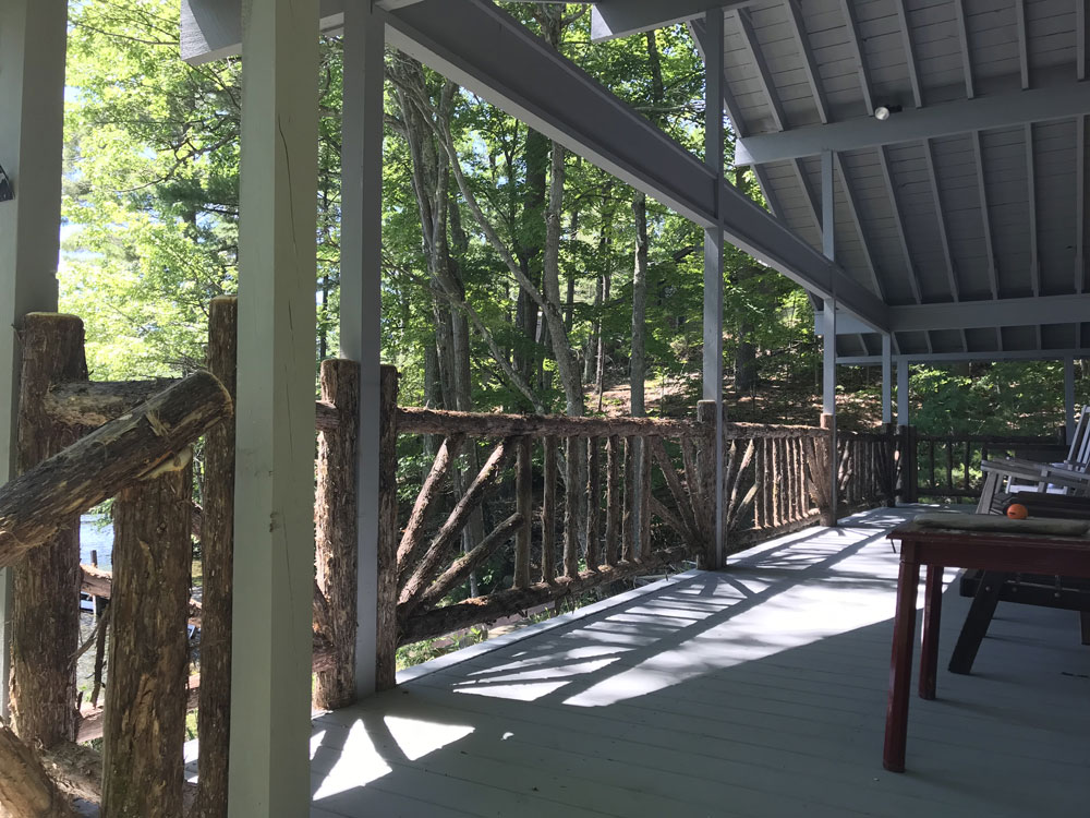 Railings built in the rustic style using logs and branches titled the Porch Railings at Hullets Landing