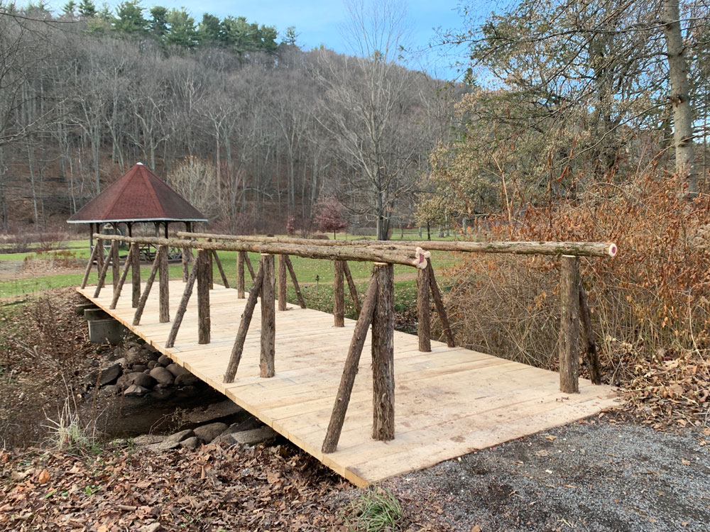 Bridge railings built in the rustic style using logs and branches titled the Kirkside Park Access Bridge