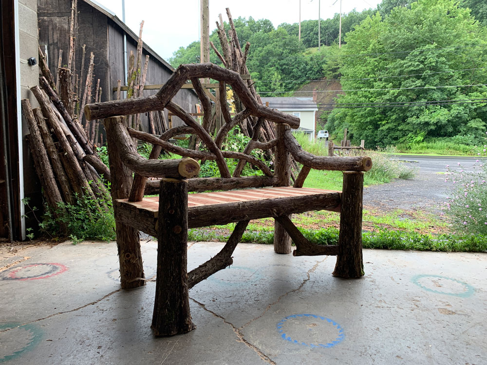 Outdoor park bench built in the rustic style using logs and branches titled the Garrison Bench