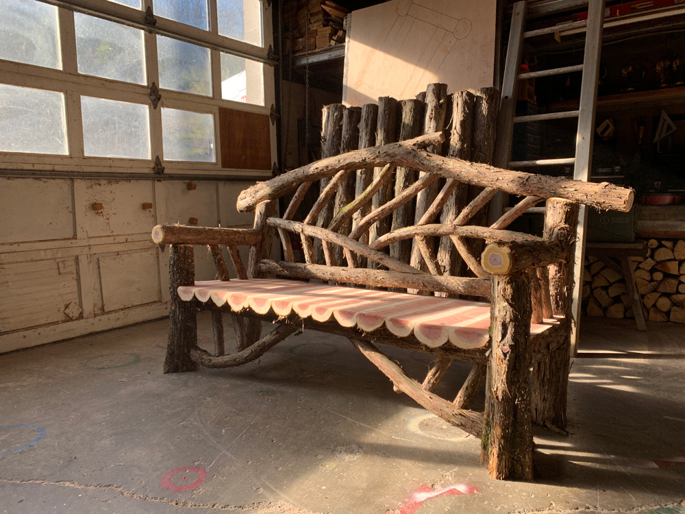 Outdoor park bench built in the rustic style using logs and branches titled the 6' Rhinebeck Bench
