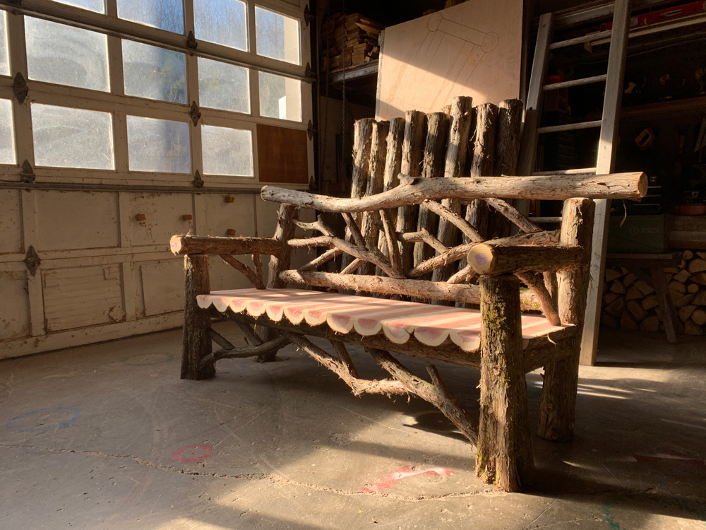 Outdoor rustic garden bench built using bark-on trees and branches titled the 6' Animal Kingdom Bench