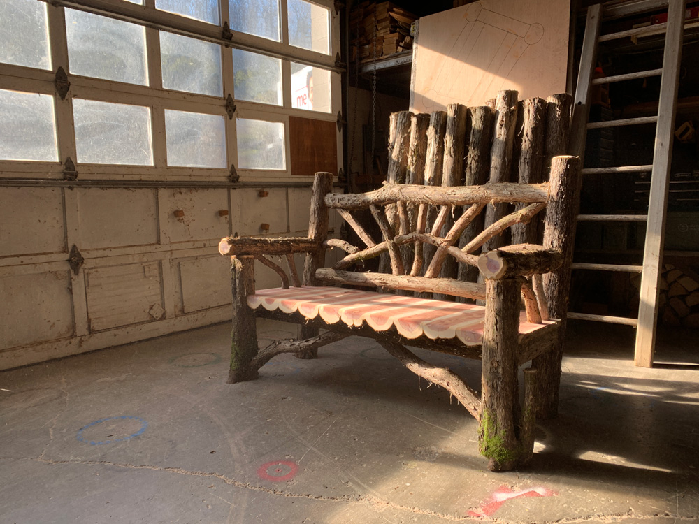 Outdoor park bench built in the rustic style using logs and branches titled the 5' Waterloo Bench