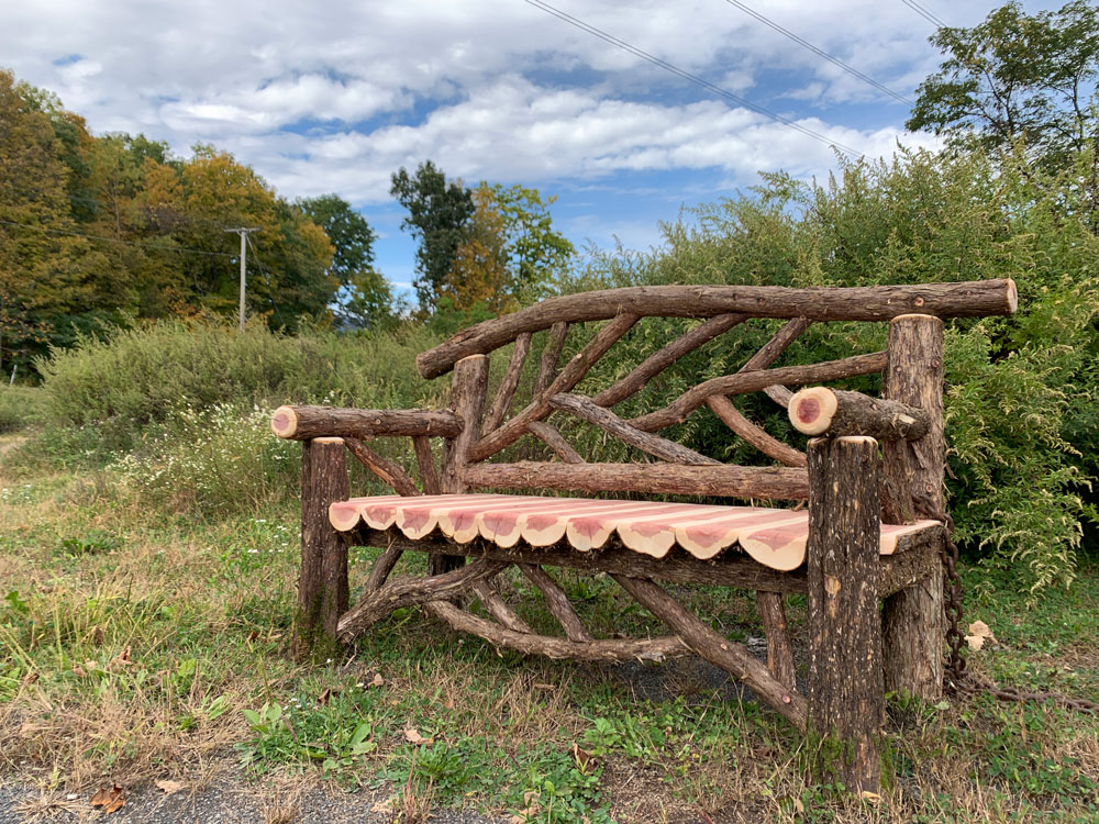Outdoor park bench built in the rustic style using logs and branches titled the Rhinebeck Bench