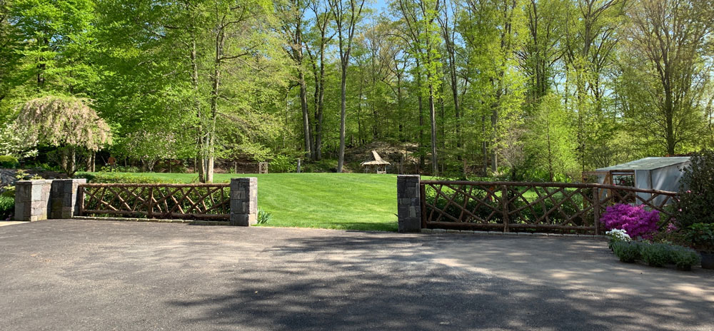 Rustic garden fencing built using bark-on trees and branches titled the Ossining Fencing