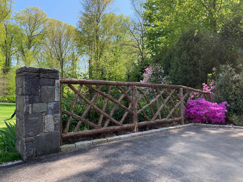 Rustic fencing custom built using cedar trees and branches titled the Ossining Fencing