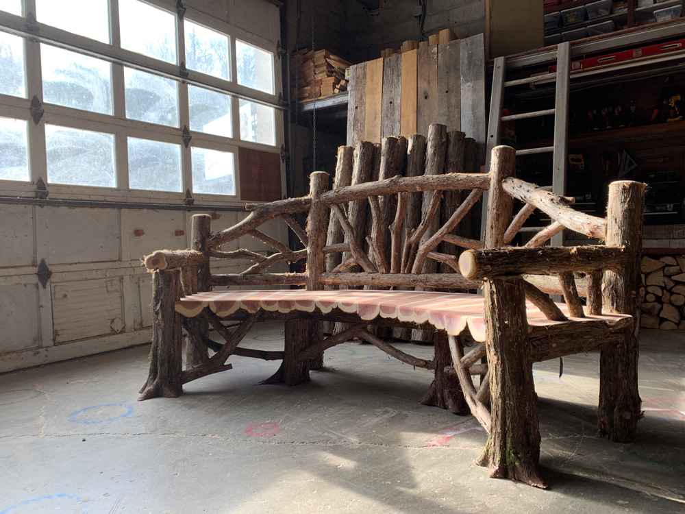 Outdoor rustic garden bench built using bark-on trees and branches titled the Poet's Bench
