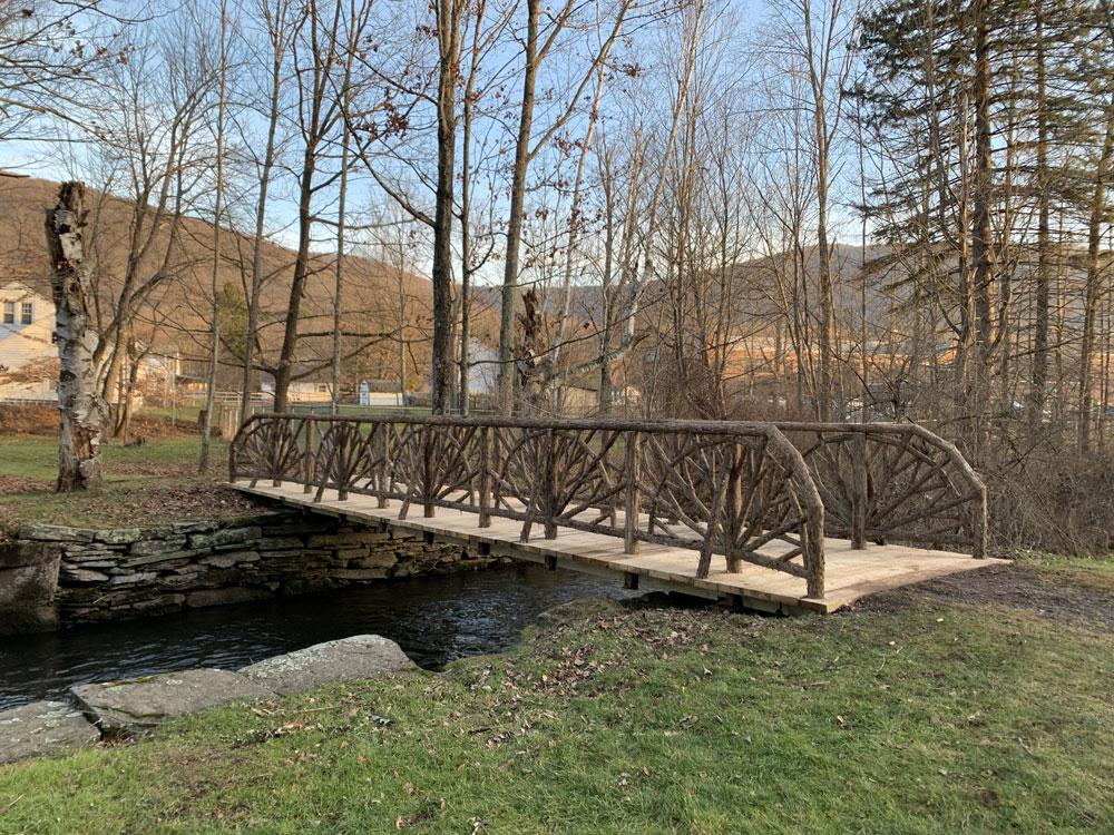 Rustic bridge railings built using bark-on trees and branches installed at Kirkside Park in Roxbury NY