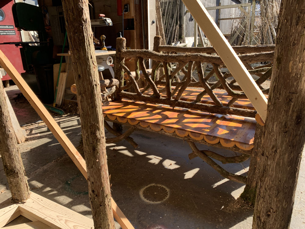 Natural wood bench built with trees and branches titled the Mohonk Bench