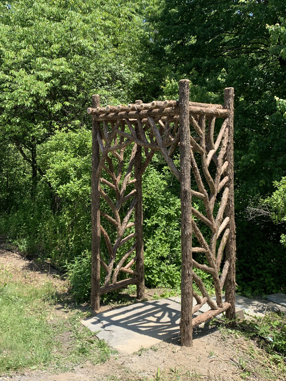 Rustic natural arbor made from bark-on cedar logs, twigs, and branches titled the Tyson Arbor
