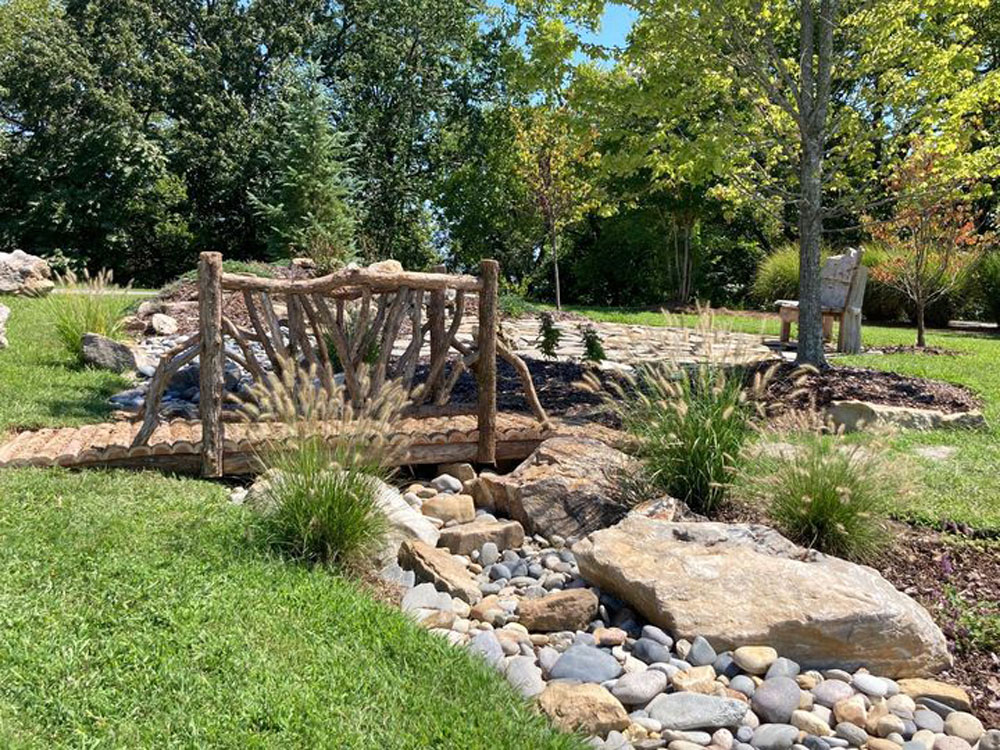 Bridge built in the rustic style using logs and branches titled the East Branch Bridge