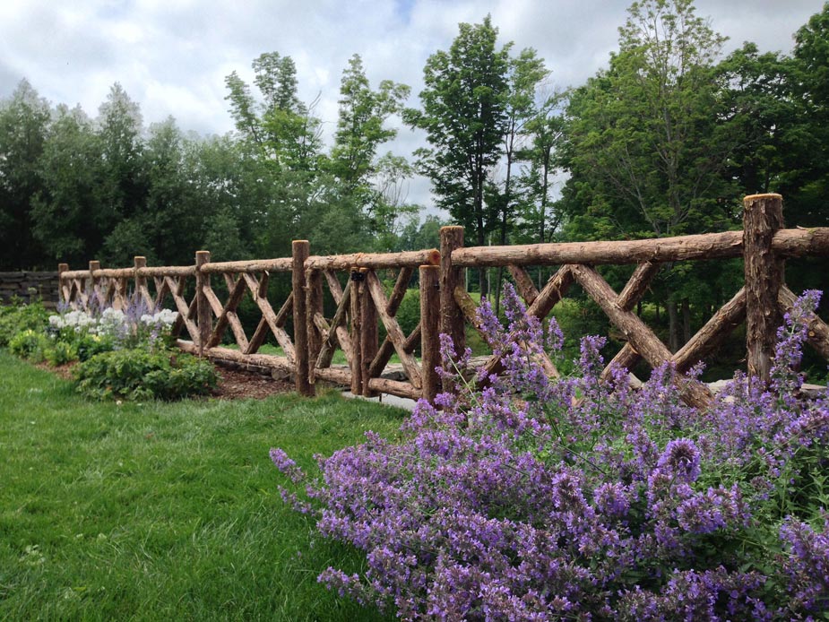 Rustic garden fencing built using bark-on trees and branches titled the Old Chatham Fencing